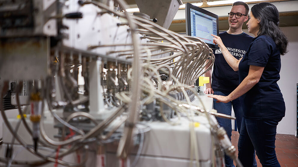 A female scientist and a male scientist from Paderborn University work together on a machine.